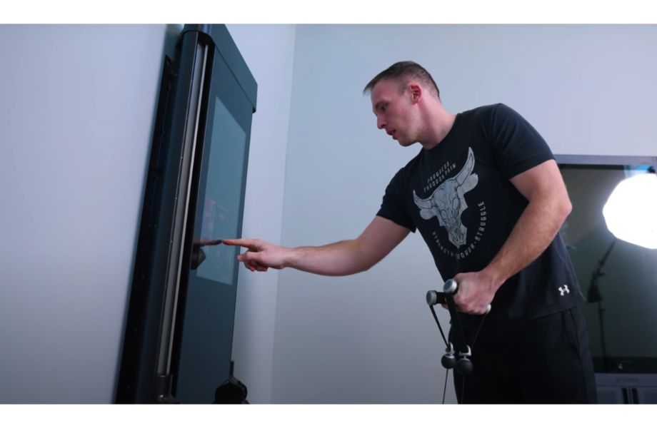 Anthony using the touchscreen of a Tonal Smart Home Gym Machine