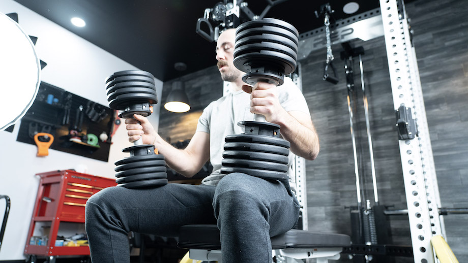 Man on a weight bench holding the 55-lb NordicTrack Adjustable Dumbbells