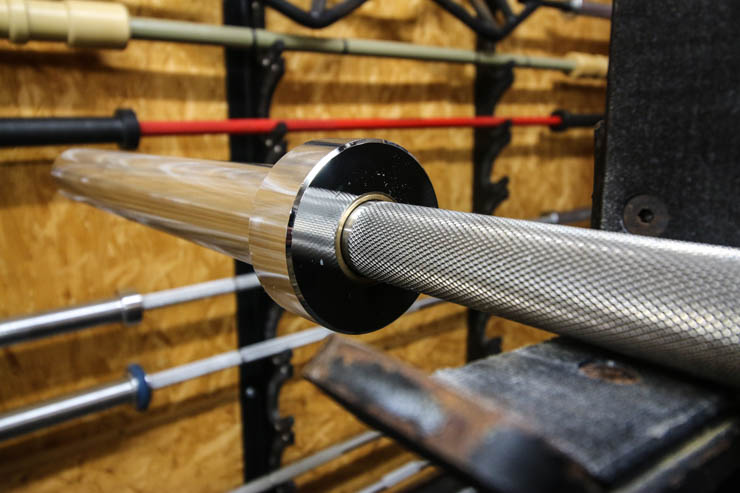 The stainless steel Rogue Ohio Bar resting on a squat rack's J-hooks