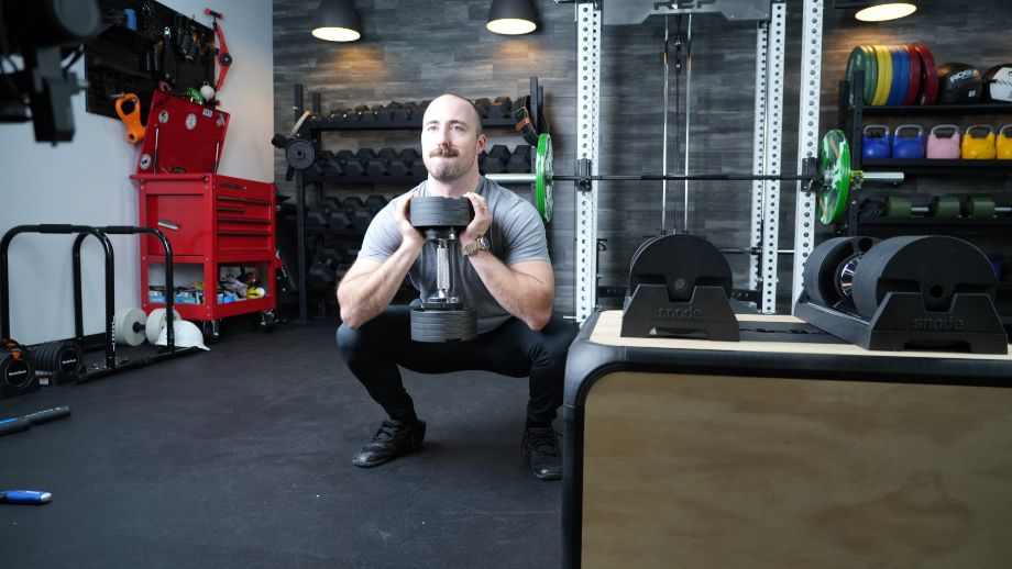 Man performing a goblet squat using the Snode AD80 adjustable dumbbells