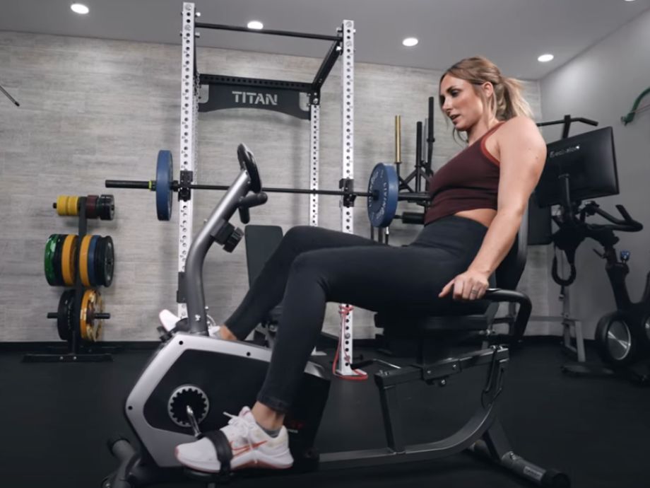 A person is shown riding a Sunny Health and Fitness Essential Recumbent Exercise Bike.