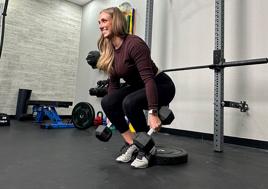 woman performing a heels-elevated dumbbell hack squat